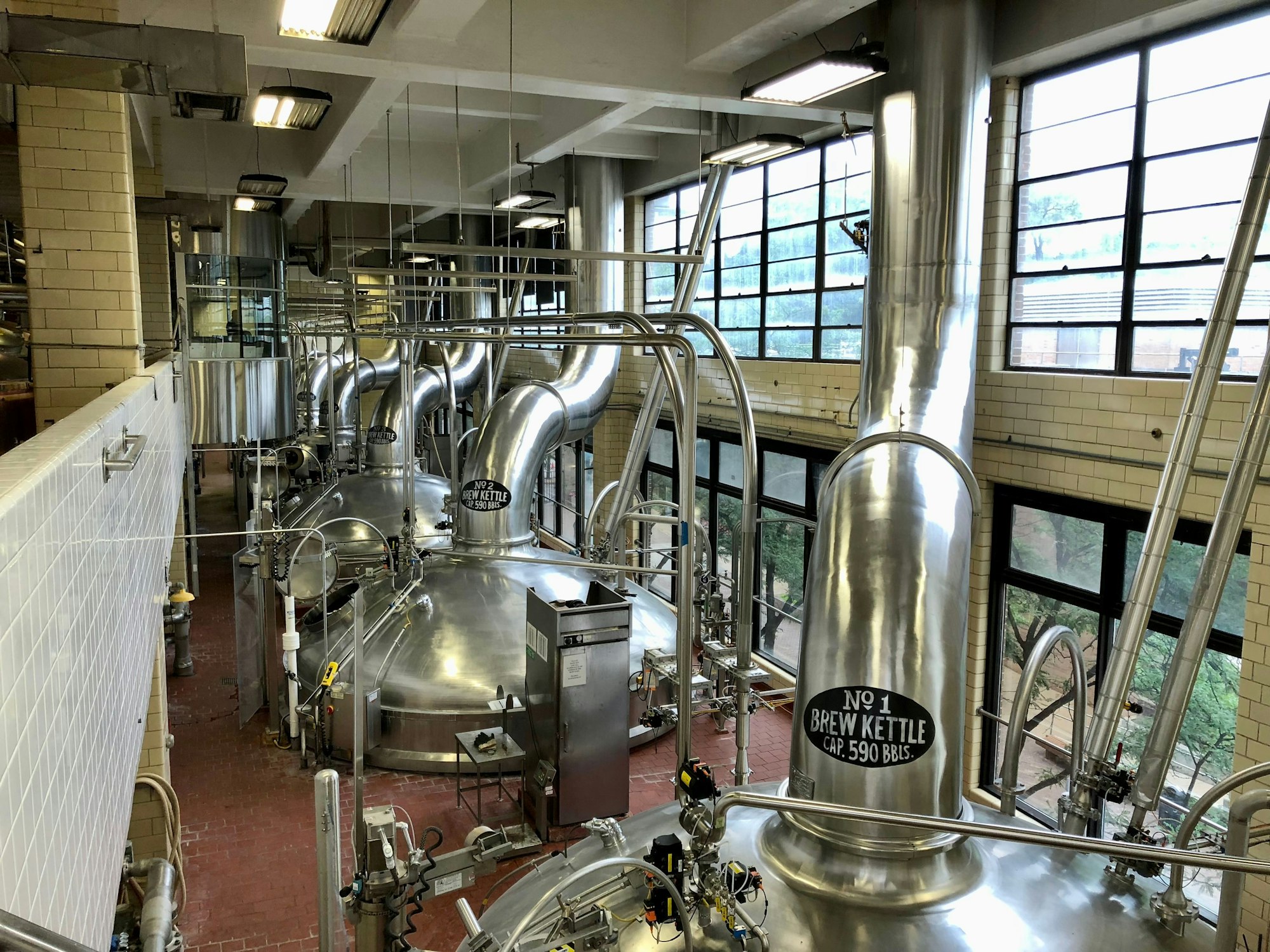 Inside of a beer factory with metallic brew kettle stations